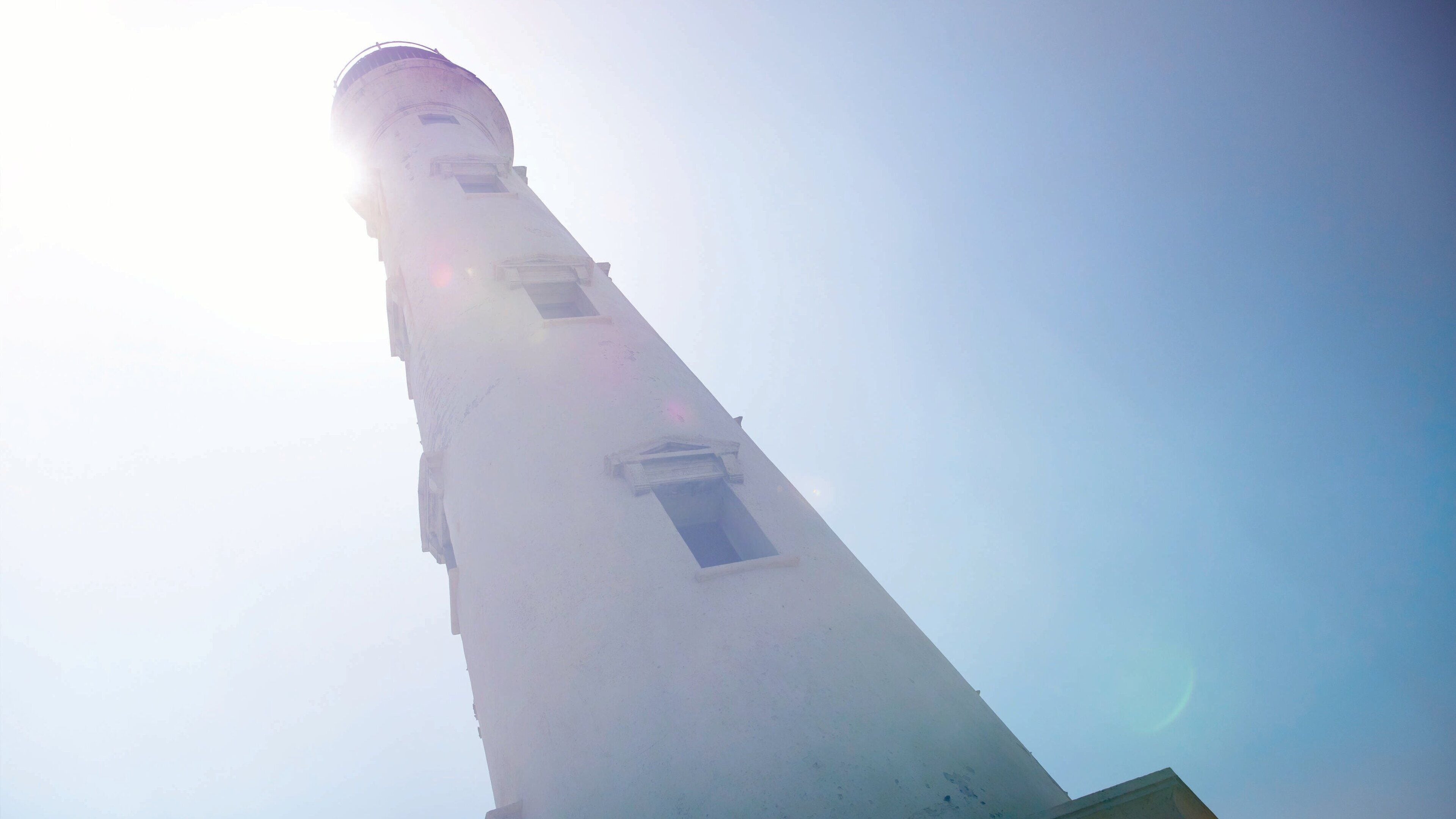 A tall tower with a narrow window and a bell at the top.