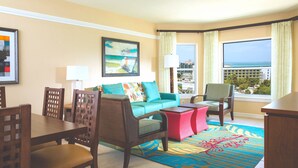 A hotel room with a sofa, chairs, a dining table, and a view of the ocean. - Oceanside - 2 Bedroom - Marriott's Aruba Surf Club - Full Resort Access (Palm Beach)