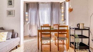 Una sala de estar acogedora con un sofá, una mesa de comedor con sillas y una pequeña zona de cocina con un carrito.