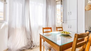 Un comedor con mesa de vidrio, sillas de madera y un cuenco de fruta.