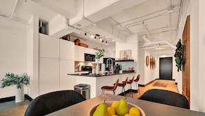 Une cuisine moderne avec des meubles blancs, un îlot central et un coin repas comprenant une table et des chaises.