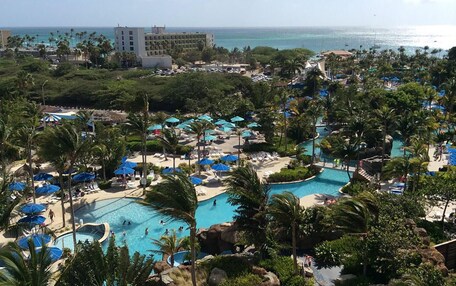 A resort with multiple swimming pools, palm trees, and a view of the ocean.