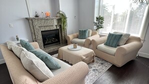 A living room with a fireplace, two sofas, a coffee table, and a ceiling fan. - Spacious upper-level unit located on Main St. (Vancouver)