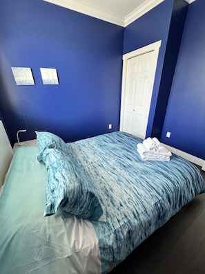 A bedroom with a bed, a white door, and two framed pictures on the wall. - Spacious upper-level unit located on Main St. (Vancouver)