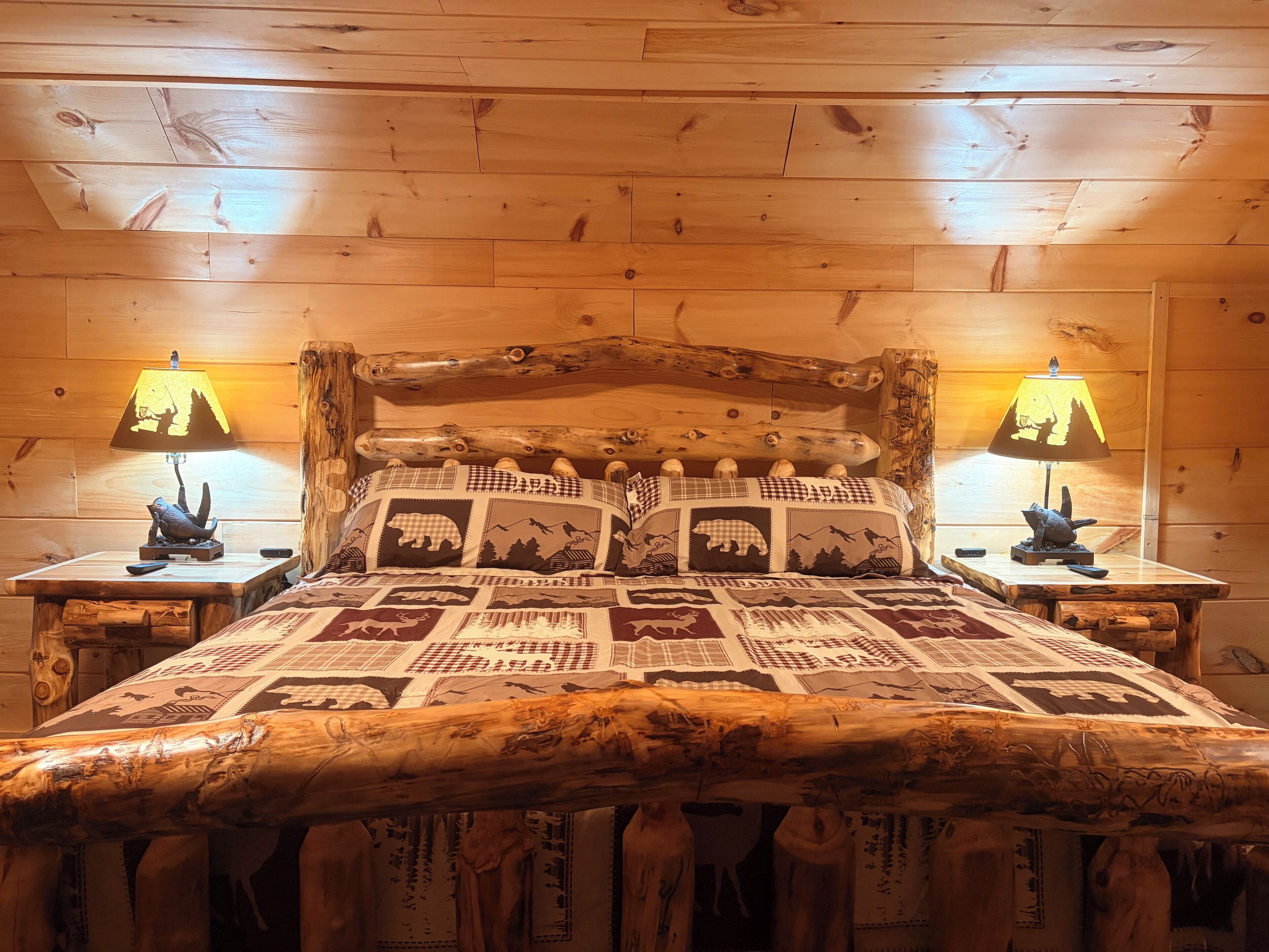 A wooden bed with a quilted headboard, two bedside lamps, and a rustic wooden headboard.