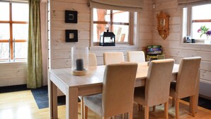 A wooden interior with a dining table and chairs, framed pictures, a clock, and a window with curtains. - Cozy home in Norheimsund with sauna (Norheimsund)