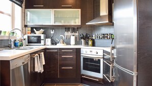 A modern kitchen with dark cabinetry, a stainless steel refrigerator, a built-in oven, and a microwave. - Cozy home in Norheimsund with sauna (Norheimsund)