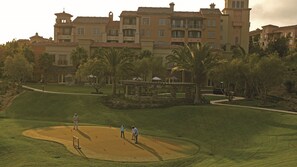 A golf course with a clubhouse and a large building in the background.