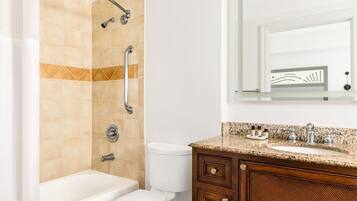 A bathroom with a shower, toilet, and vanity with a sink and mirror.