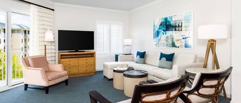 A modern living room with a sofa, armchairs, a coffee table, a flat-screen TV, and a painting on the wall.