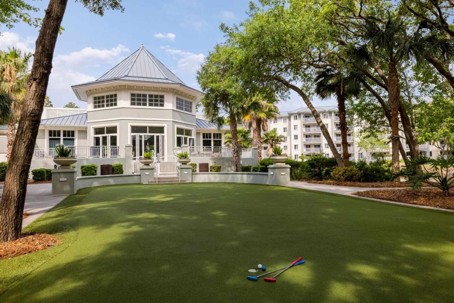A golf course with a clubhouse and a building in the background.