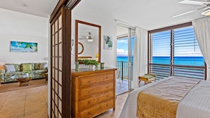 A hotel room with a balcony, a bed, a dresser, and a sofa. - Oceanfront Maui Escape with Private Lanai, Pool & Stunning Views (Lahaina)