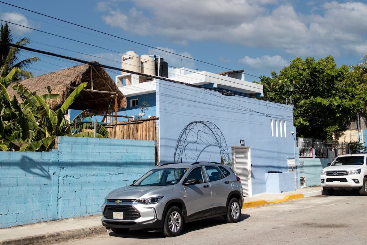 A silver SUV parked in front of a building with a blue wall and a large mural.