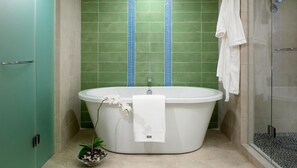 Ein Badezimmer mit einer freistehenden Badewanne, einem weißen Handtuch und einer kleinen Pflanze.