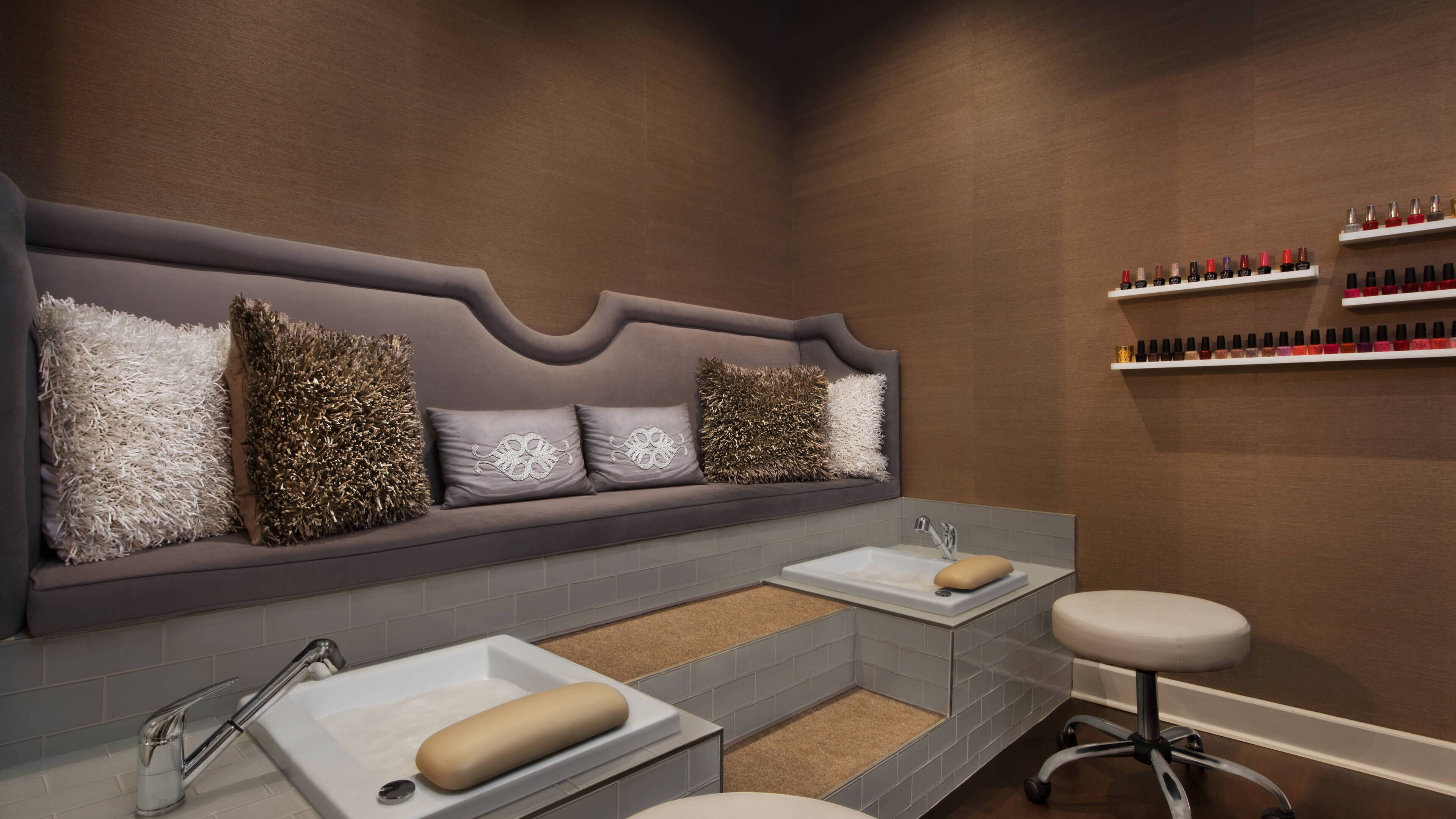 Un baño moderno con un banco gris, dos lavamanos y un taburete.