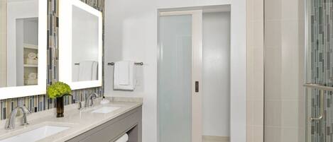 Un baño moderno con dos lavabos, un espejo grande y una zona de ducha.