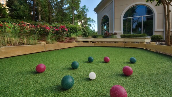 A croquet field with balls and a building in the background.