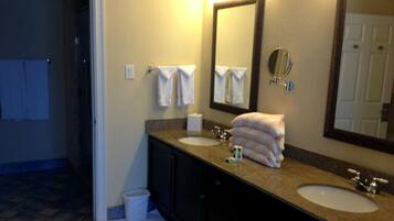 A bathroom with two sinks, a large mirror, and a towel rack with folded towels.