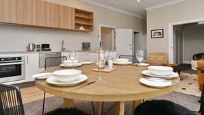 A modern kitchen with white cabinets, a built-in oven, and a dining area with a round wooden table set for four. - Kaiapoi Luxury Accommodation 1 -Historic and Luxury Apartment in Kaiapoi (Kaiapoi)