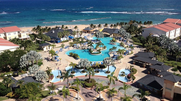 A resort with multiple swimming pools, beach access, and palm trees.