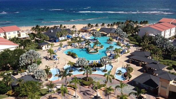 A resort with multiple swimming pools, beach access, and palm trees.