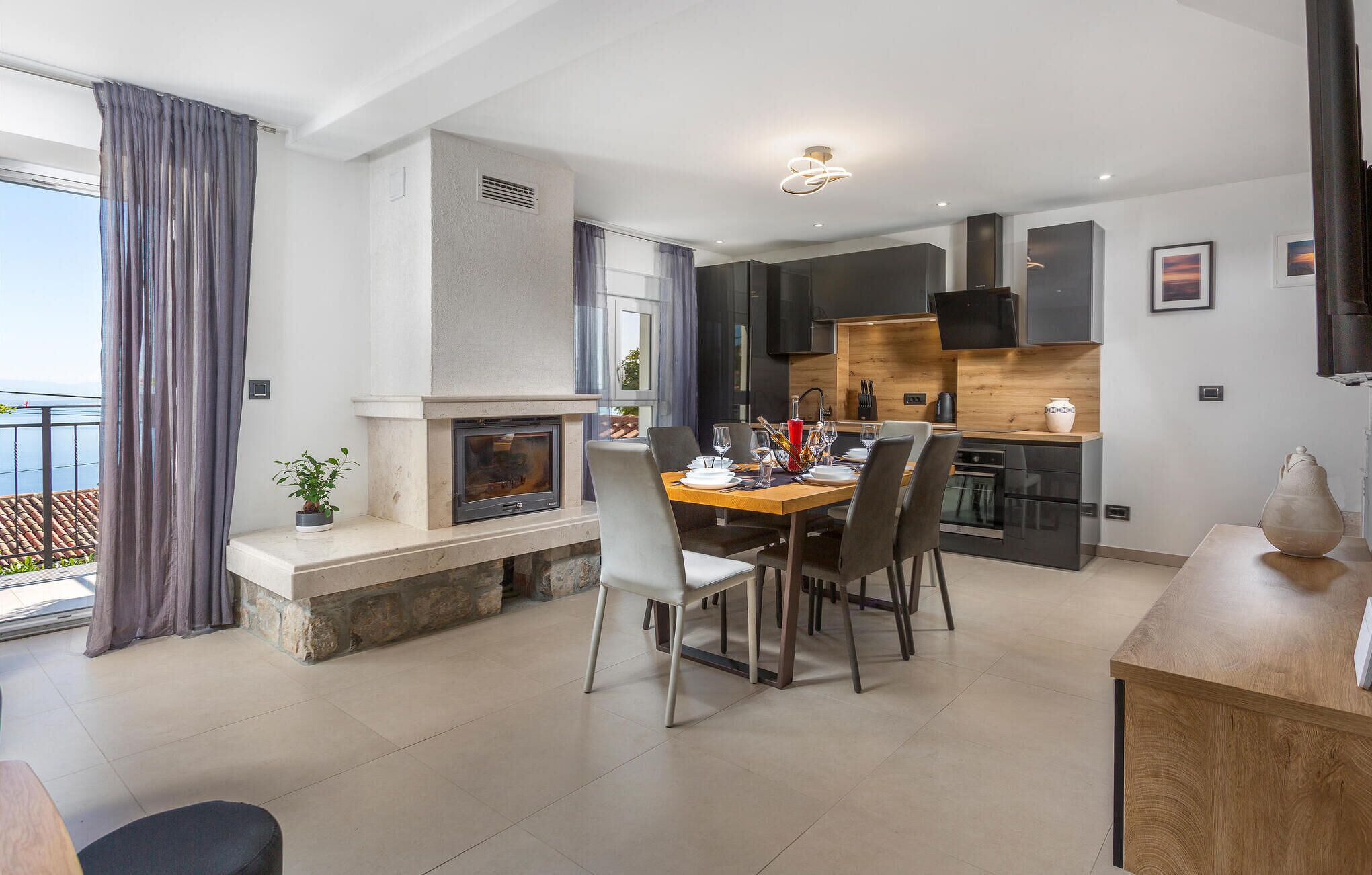 Una cucina moderna con forno integrato, un'area pranzo con tavolo e sedie in legno e un camino.