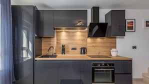 Een moderne keuken met donkere kastjes, een houten aanrechtblad, een inbouwoven en een roestvrijstalen spoelbak.