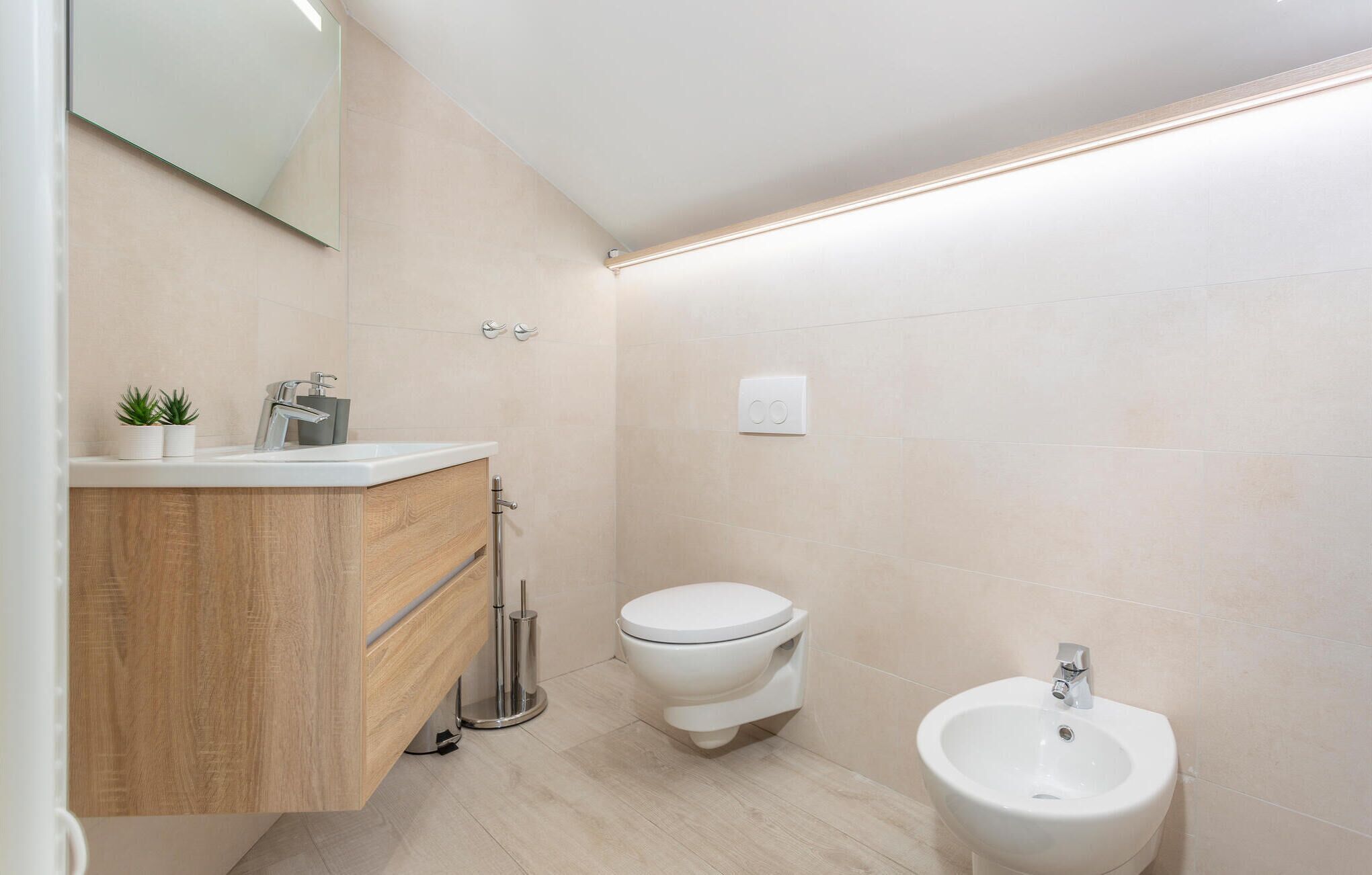 Un bagno moderno con un mobile bagno in legno, un water e un bidet.