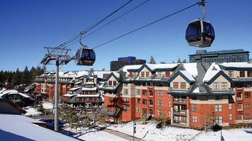 A ski resort with traditional chalet-style buildings, a cable car system, and a snowy landscape.