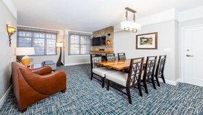 A dining area with a wooden table and chairs, a stone fireplace, and a television mounted on the wall.