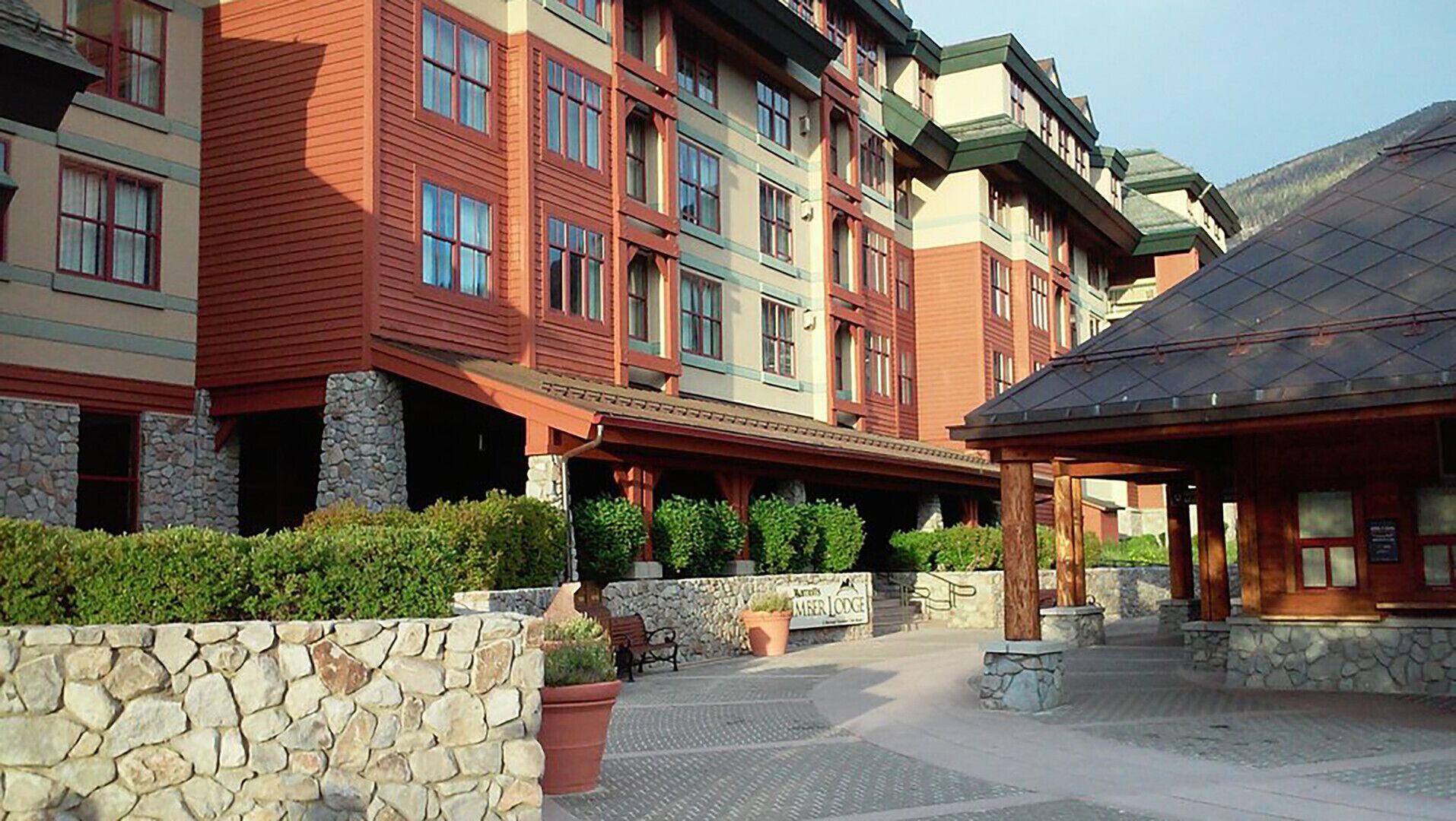 A multi-story hotel with a stone facade, multiple balconies, and a covered outdoor area with seating.