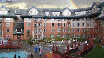 A hotel with multiple floors, outdoor swimming pool, and lounge area with umbrellas.