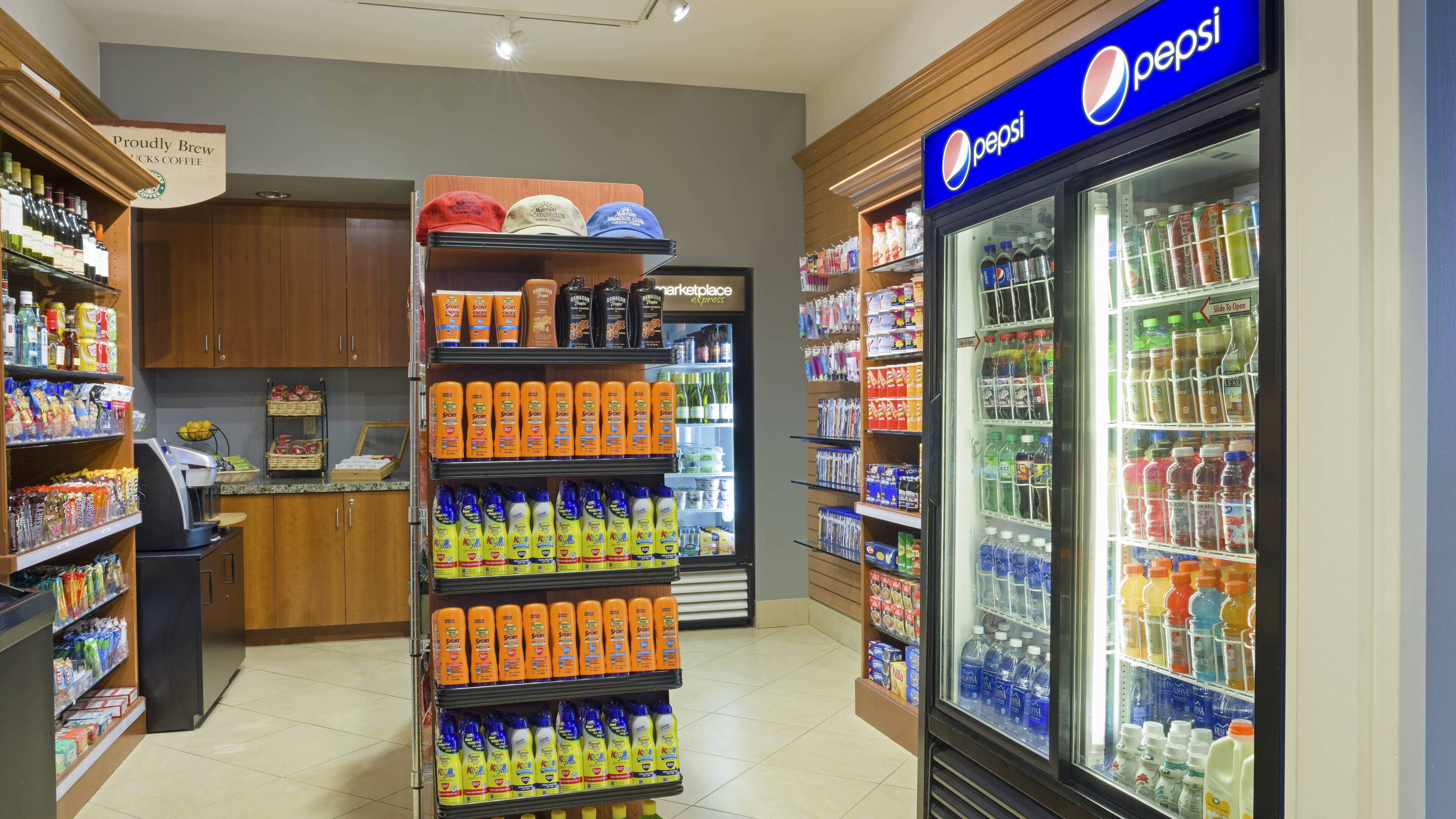 A grocery store with a refrigerated display of Pepsi and a shelf stocked with sports drinks and personal care products.