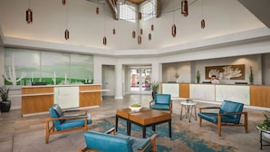 A spacious lobby with a reception desk, seating area, and artwork on the walls.