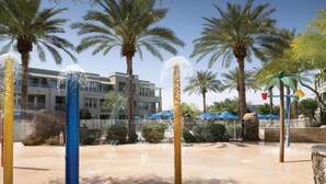A water feature with multiple jets, palm trees, and a building in the background.