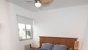 Un dormitorio con cama, cabecera de madera, mesita de noche, lámpara y ventilador de techo.