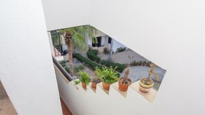 Una escalera con una pequeña ventana que da a un jardín con plantas en macetas.