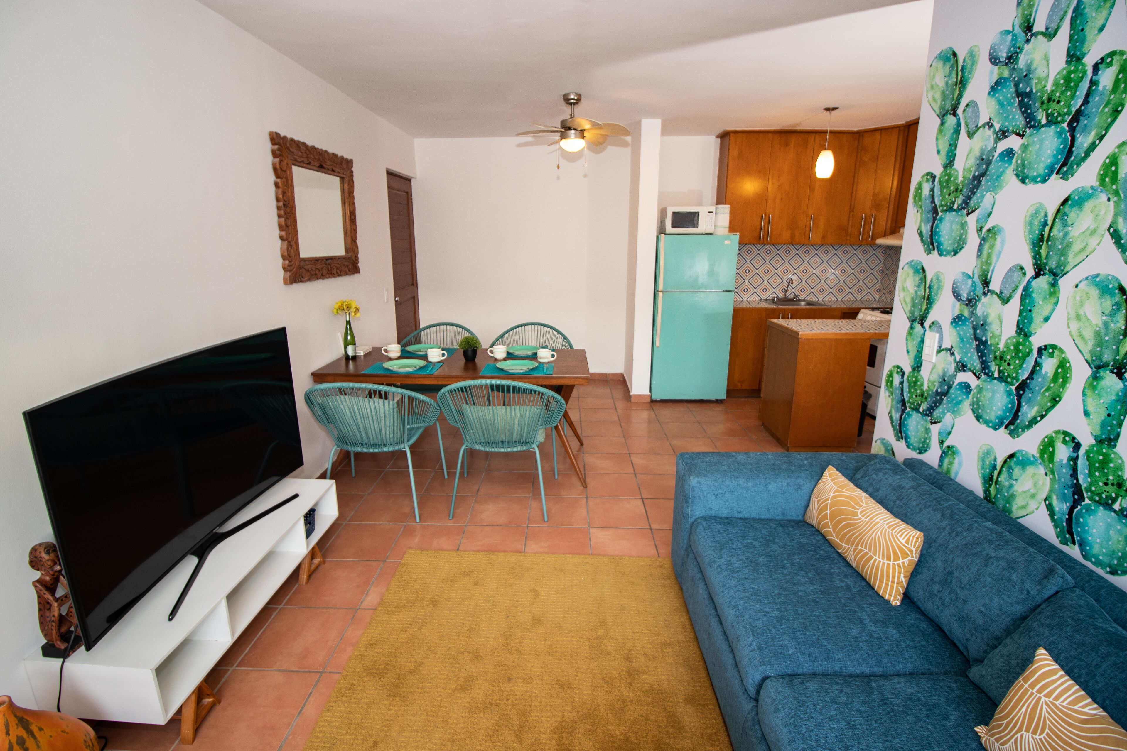 A living room with a TV, sofa, and dining area with chairs.