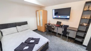 A hotel room with a bed, a desk, a chair, a TV, and a wardrobe. - Ensuite style Studio in Selly Oak (Birmingham)