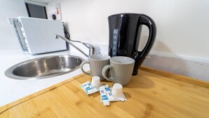 A kitchen counter with a coffee maker, two mugs, and packets of coffee creamer. - Ensuite style Studio in Selly Oak (Birmingham)