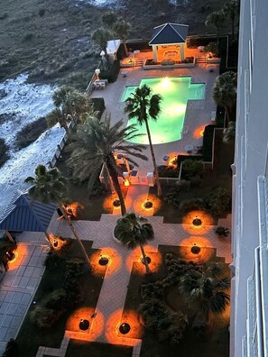 Relax by the resort's rectangular pool surrounded by palm trees and outdoor seating.