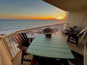 Enjoy the ocean view from this balcony with a table, chairs, and a potted plant.