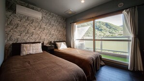 Un dormitorio con dos camas, una ventana con vistas a zonas verdes y una lámpara en el techo.