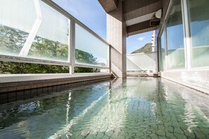 A modern indoor pool with clear water, surrounded by large windows and a tiled floor. - Few Days Condominium (Sapporo)