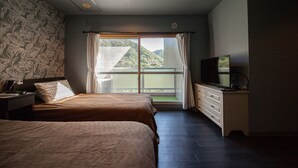 Un dormitorio con dos camas, televisión y balcón con vistas a la montaña.