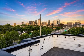 A rooftop with a city skyline view, power lines, and a street with traffic. - Stylish Nashville Stay • Skyline Views (Nashville)
