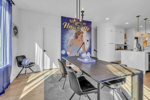 A modern dining area with a wooden table, black chairs, and a poster on the wall.