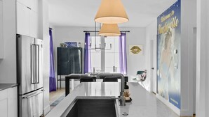 A modern kitchen with a central island, stainless steel appliances, and pendant lighting. - Stylish Nashville Stay • Skyline Views (Nashville)