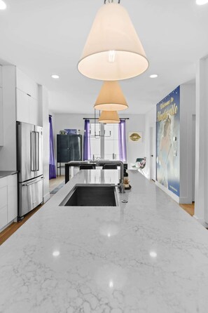 A modern kitchen with a central island, stainless steel appliances, and pendant lighting.