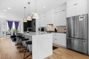 A modern kitchen with a large island, stainless steel appliances, and pendant lighting. - Stylish Nashville Stay • Skyline Views (Nashville)